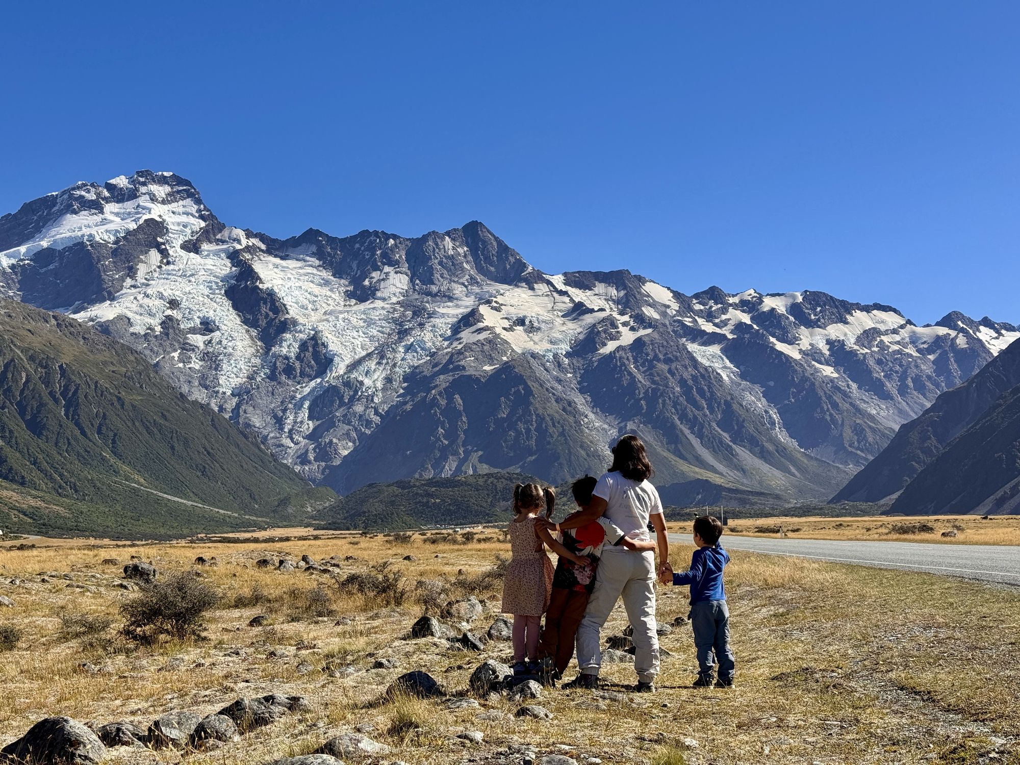 Familia contemplando una gran cordillera nevada desde una llanura