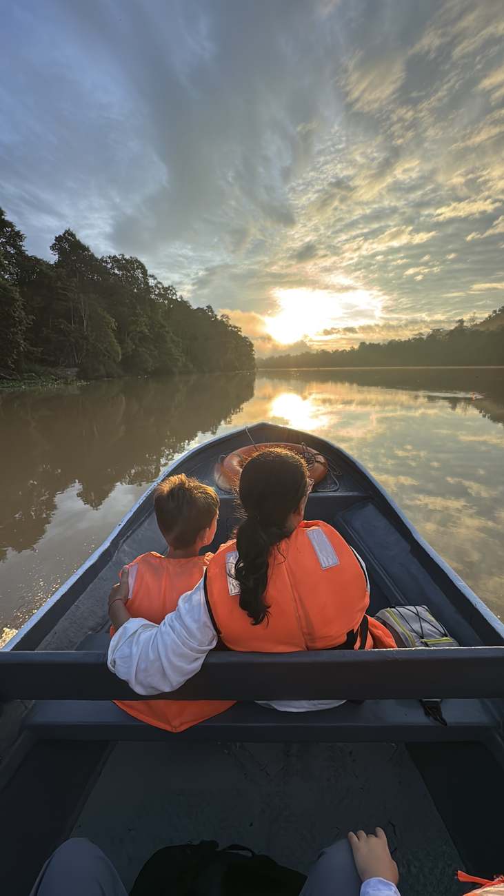 Una madre y su hijo contemplan el amanecer desde una barca en el río