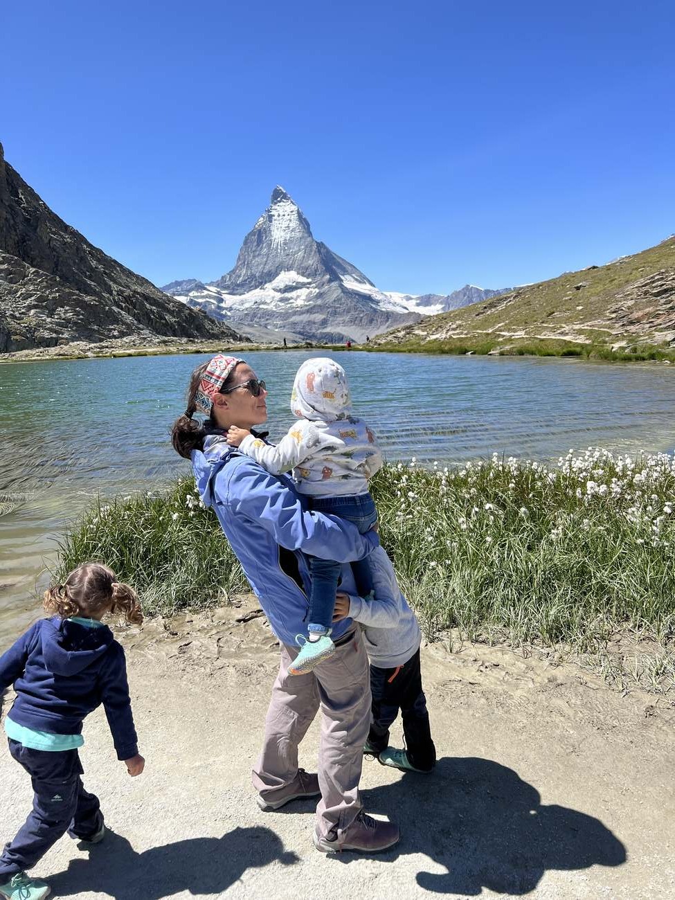 Madre con su bebé en brazos ante un lago alpino con el Matterhorn al fondo