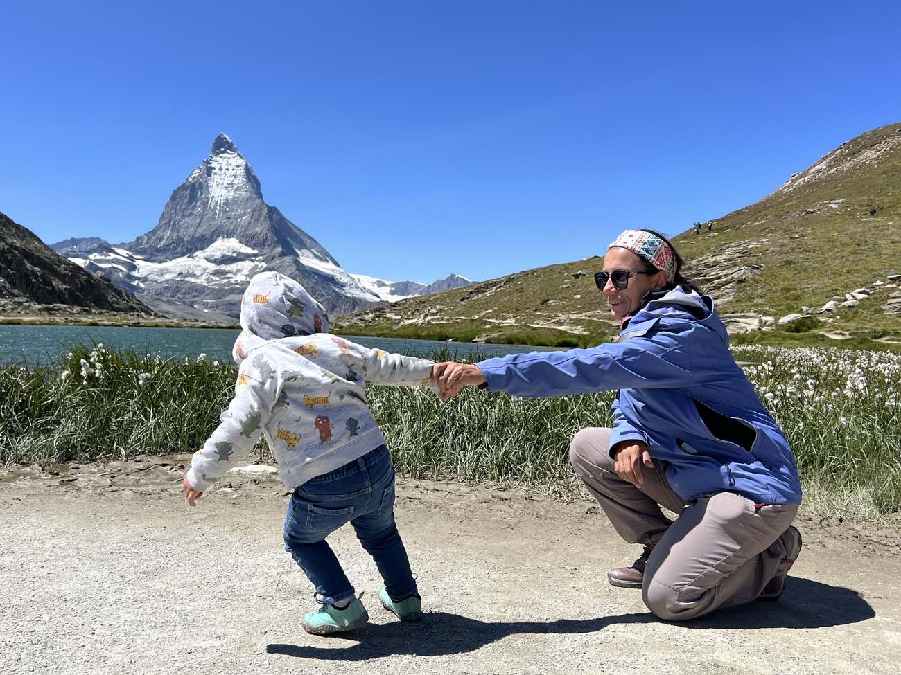 Una madre tiende la mano a su peque, que corre hacia ella ante el Matterhorn, en Zermatt, Suiza