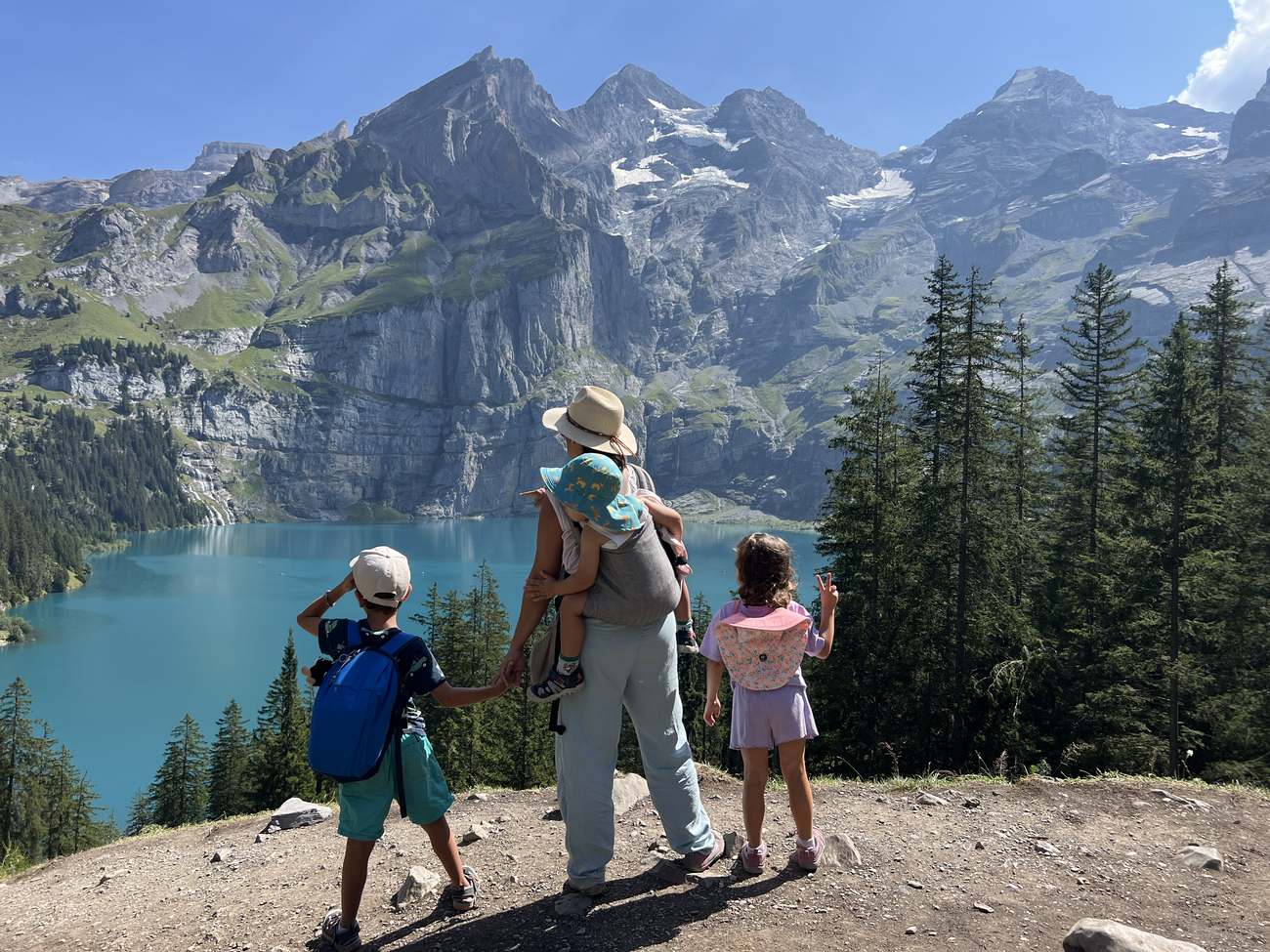 Una familia contempla el lago turquesa del Oeschinensee desde el sendero, en los Alpes suizos
