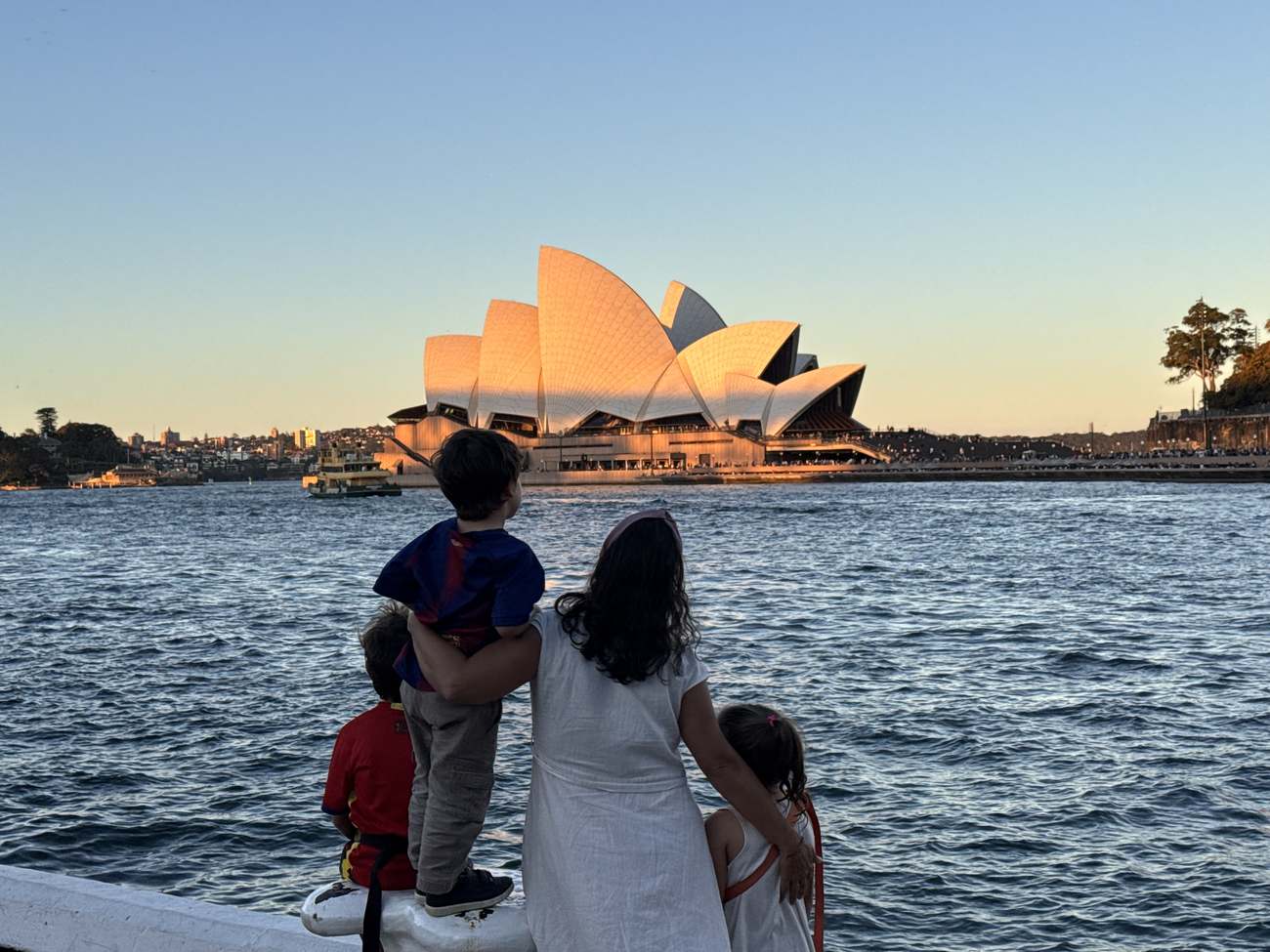 Familia de espaldas contemplando la Ópera de Sídney al atardecer