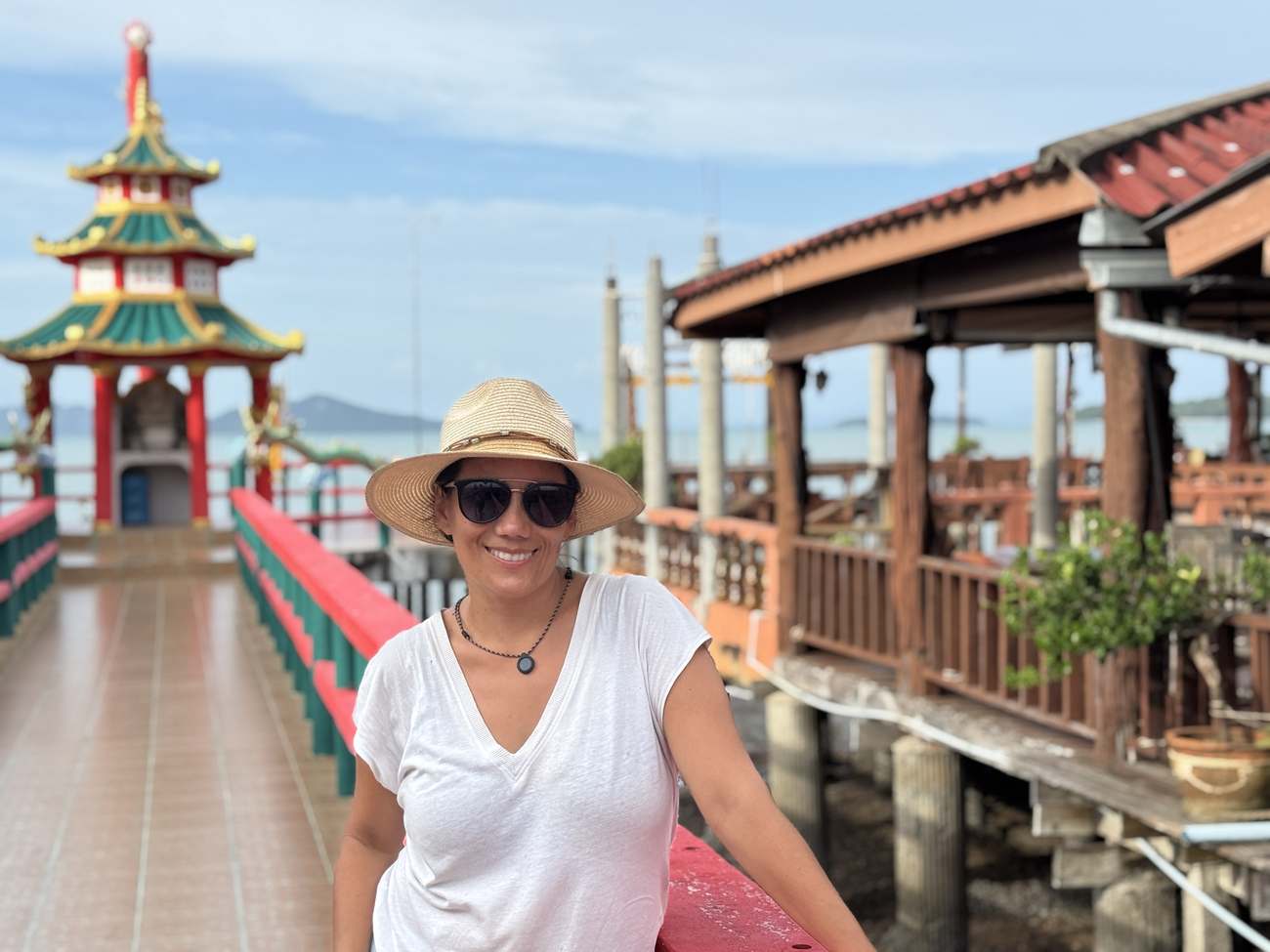 Patricia sonriendo junto a un templo oriental en un muelle junto al mar