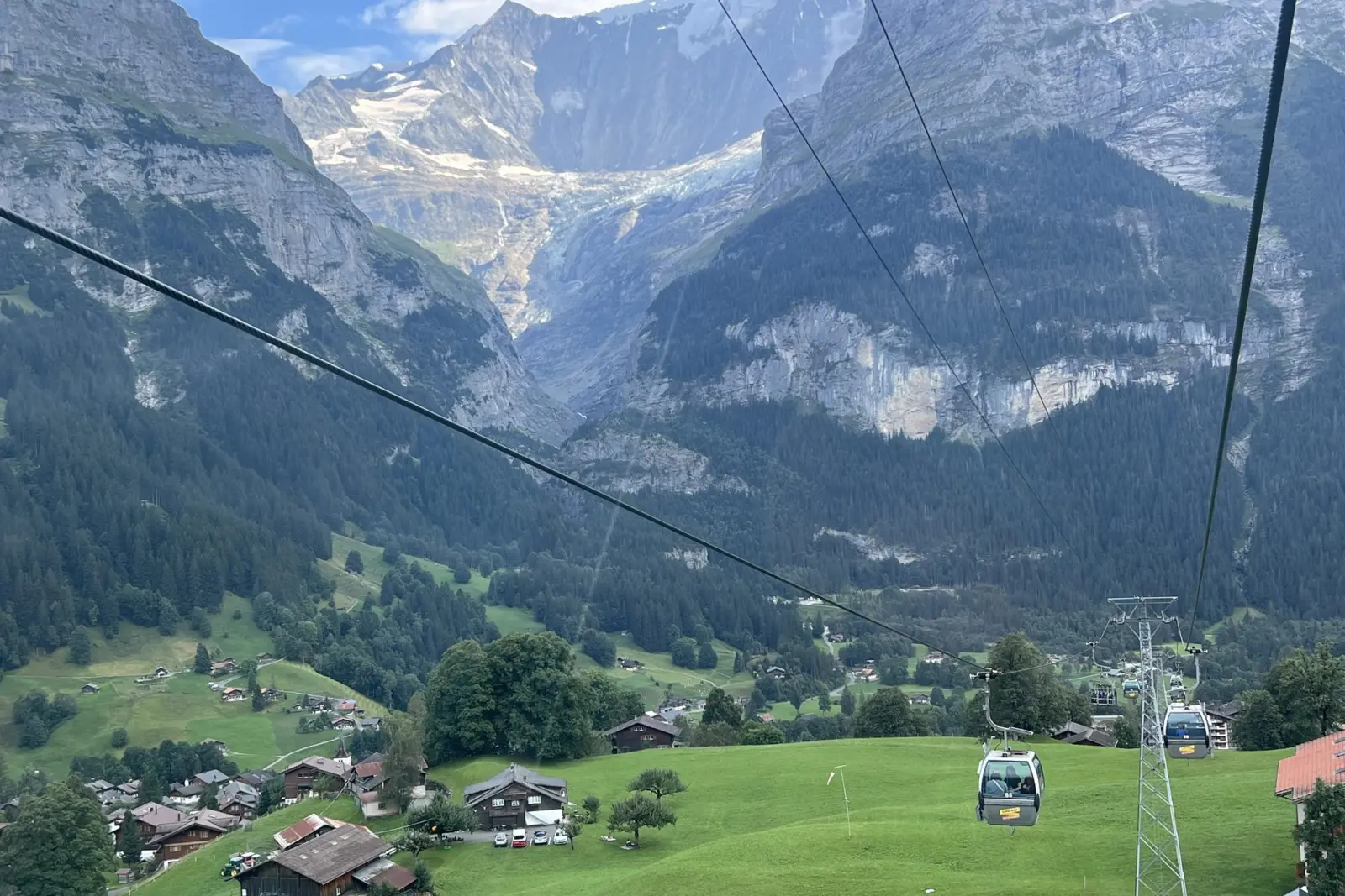 Góndola de Grindelwald First subiendo sobre el pueblo, con las montañas al fondo