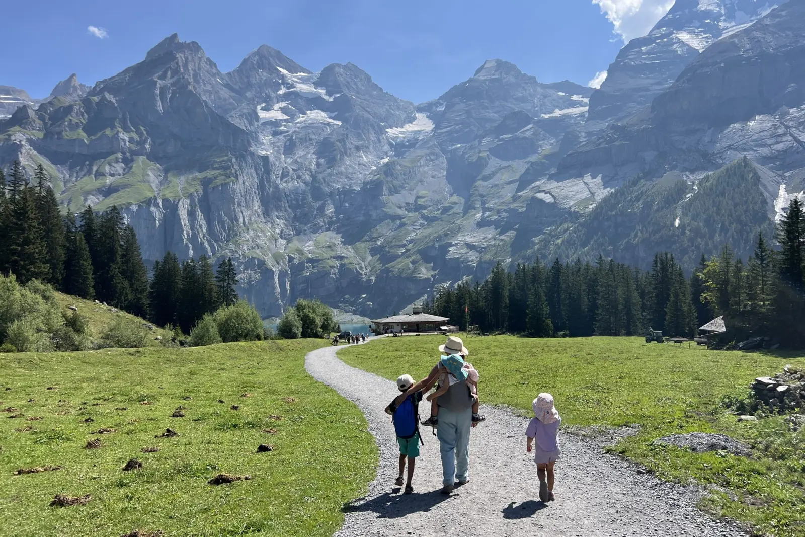 Familia de espaldas caminando por la pista hacia el lago Oeschinensee