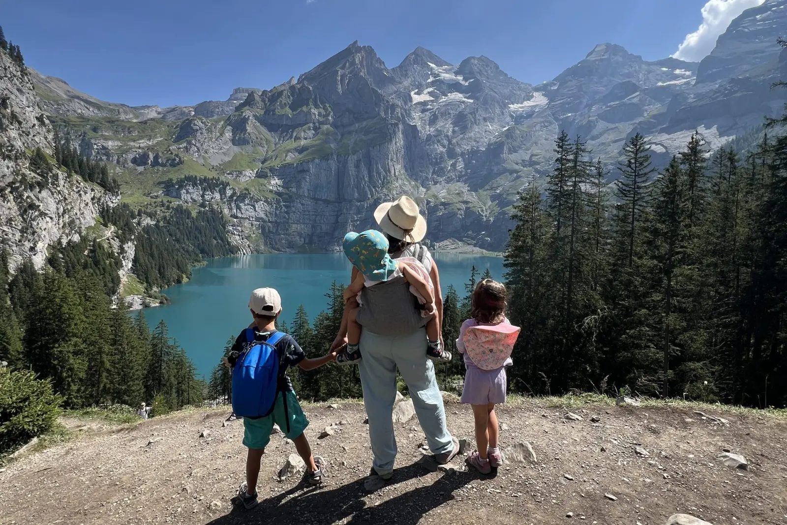 Madre con sus hijos, de espaldas, en el mirador sobre el lago Oeschinensee